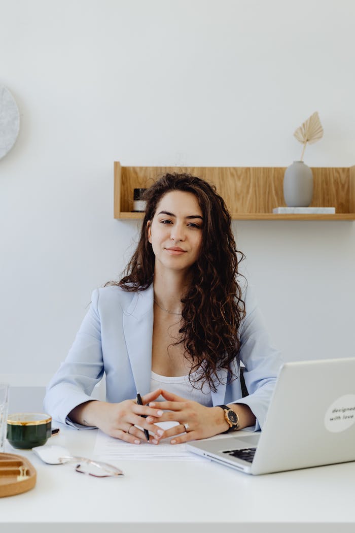 The Art of Drawing Readers In: Your attractive post title goes here Portrait of a confident businesswoman sitting at a desk with a laptop in a modern office.